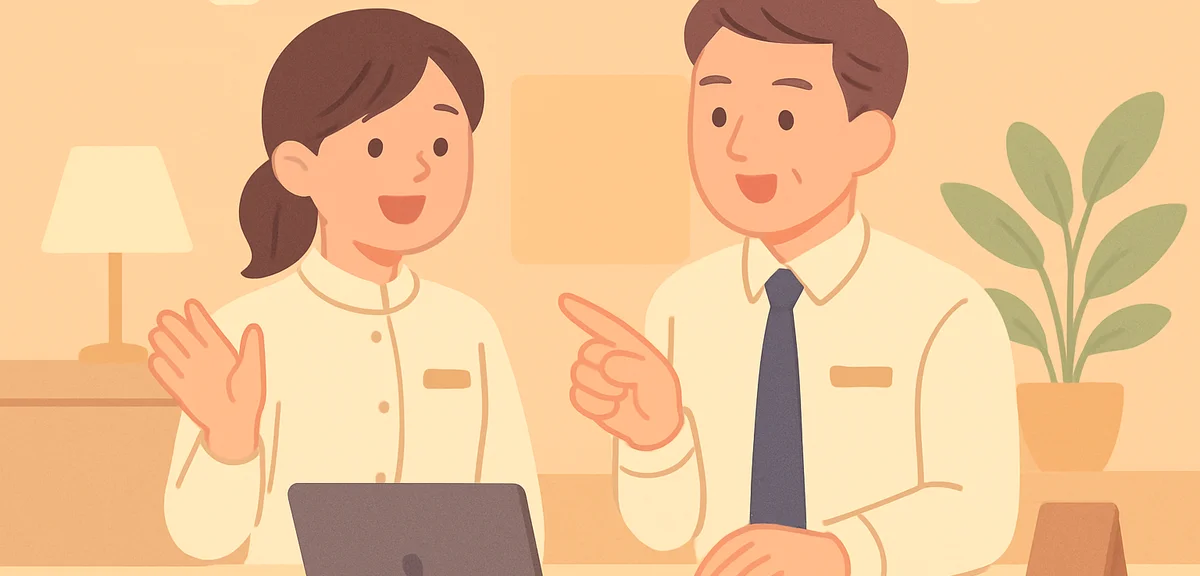 A young Japanese staff member in a clean hotel uniform learning tasks from a senior colleague at a r